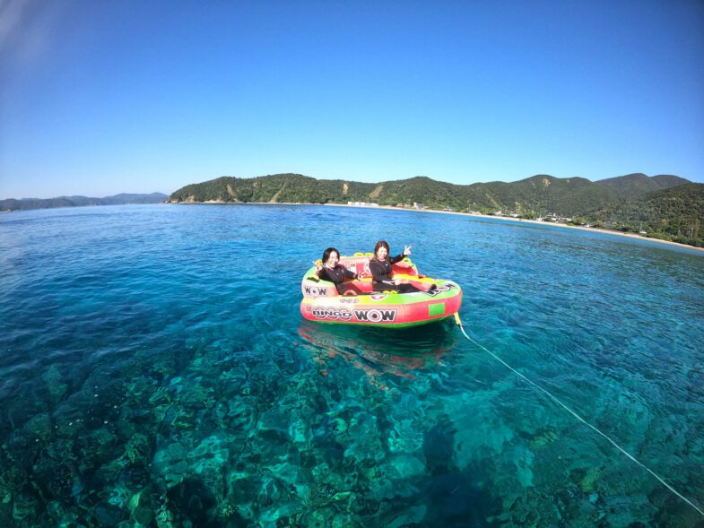 加計呂麻島が見える絶景ビーチでトーイングチューブで楽しむ様子。